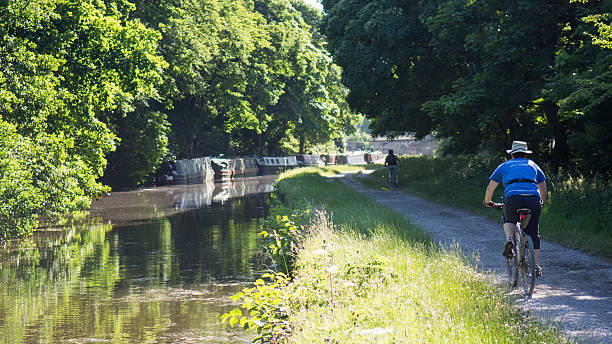 Cyclists riding along a green canal path in West Yorkshire